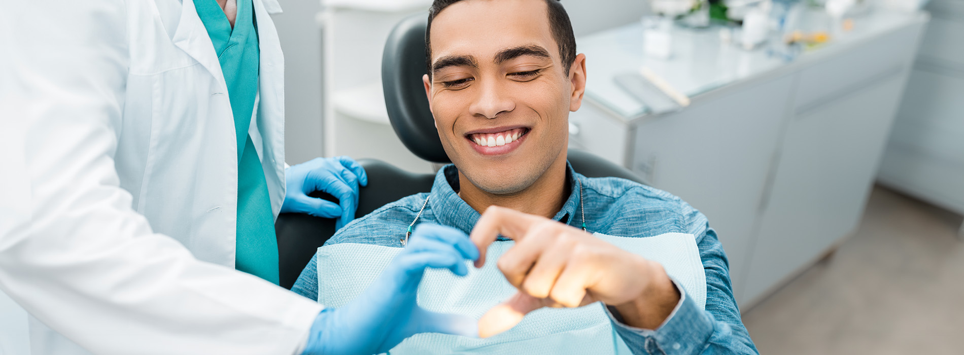 The image shows a group of people, possibly professionals given their attire and the setting that appears to be an office or professional environment. They are gathered around a table with a laptop on it, engaged in what seems to be a discussion or meeting.